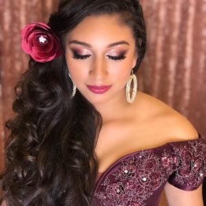 A beautiful Quinceanera woman with a flower in her hair showcasing a trendy and elegant hairstyle