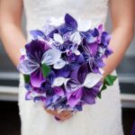 A Quinceanera holding a bouquet of purple and white flowers
