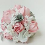 A beautiful floral design featuring a bouquet of pink and white flowers, placed on a table for a Quinceanera celebration.