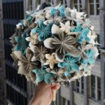 A person holding a Quinceanera flower bouquet made of cut flowers and paper flowers