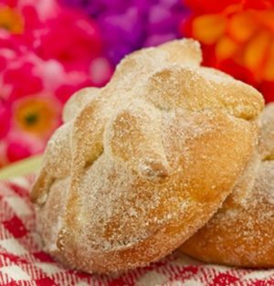 Pan de muerto en el altar de muertos, pan dulce and a couple of doughnuts sitting on top of a red and white checkered