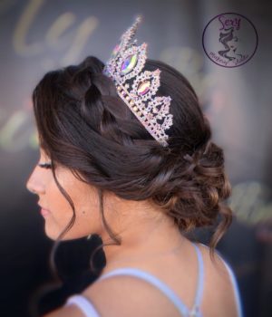 A woman wearing a crown tiara and a tiable on her head at a Quinceanera event