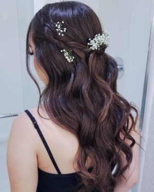 A woman in a black Quinceanera dress wearing a headpiece hairstyle with a flower in her hair