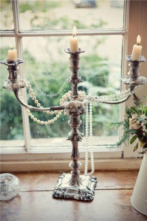 A silver candelab with pearls and candles from the Victorian era, displayed on a window sill