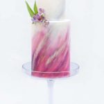 Quinceanera cake with purple watercolor design, featuring a chocolate base and a white and pink cake with a flower on top