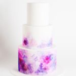 A Quinceanera cake, featuring a purple and blue minimalist watercolor design on three tiers.