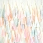 A close up of a wall with a bunch of Quinceanera tassels and a Quinceanera dress design.
