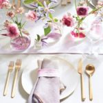 A Quinceanera themed image featuring floral design with cut flowers, displayed on a white plate and topped with a pink napkin.