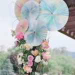 A quinceanera decoration featuring a beautiful floral design with cut flowers and a wooden structure adorned with a bunch of hanging umbrellas.
