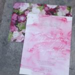 A close up of a Quinceanera invitation on a table, featuring petal Textile design