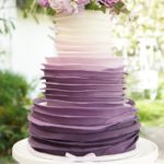 Quinceanera cake: A purple and white Quinceanera cake decorated with flowers on top