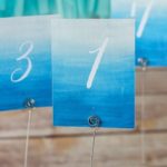 A row of blue and white place cards with numbers on them, created with a watercolor painting technique, for a Quinceanera celebration