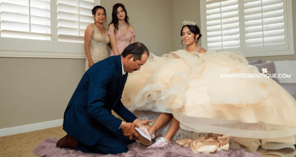 Quinceanera celebration with a woman in a pink dress, a man in a blue suit, and a bride in a Quinceanera gown