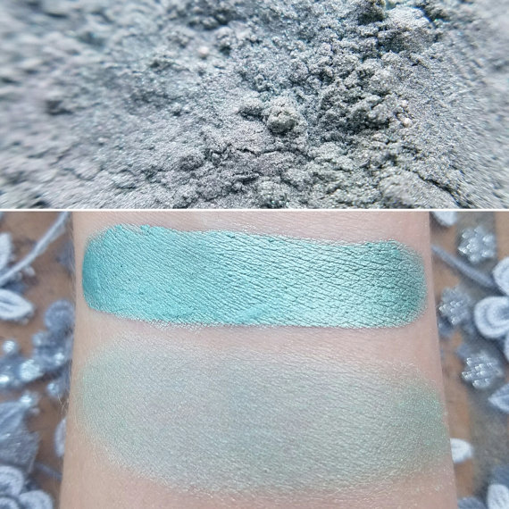 A close up of a person's arm with turquoise makeup, showcasing blue and green eye shadow in a Quinceanera theme