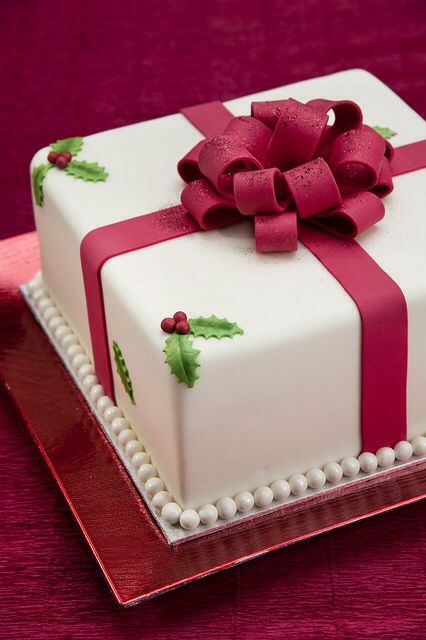 Quinceanera cake, a white cake with a red bow on top, in a square shape
