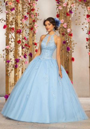 Quinceanera: Morilee, a woman in a blue ball gown standing in front of flowers.