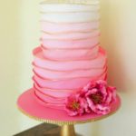 Quinceanera cake, an elegant pink and white ombre cake with a flower on top