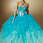 Quinceanera gown, a woman in a blue dress posing for a picture