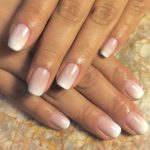 A close up of a person's hands with French manicured baby boomer nails for a Quinceanera
