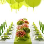 A table decorated with lime green party decorations and a bunch of green and pink flowers