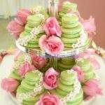 A Quinceanera macaron display featuring a three-tiered cake with pink flowers on it