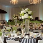 A beautiful Quinceanera centrepiece floral design in a banquet room with black and white tables and chairs