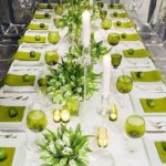 A long table is set with green place settings, showcasing green table decoration ideas for a Quinceanera celebration.