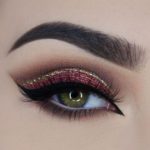 Close-up of a woman's eye with hunter green eyeshadow and red and gold eyeliner for a Quinceanera