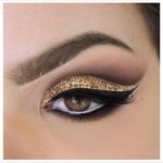 A close up of a woman's eye with gold glitter makeup for a Quinceanera