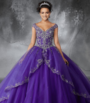 Two Quinceañera dresses, one in purple, and a woman posing for a picture