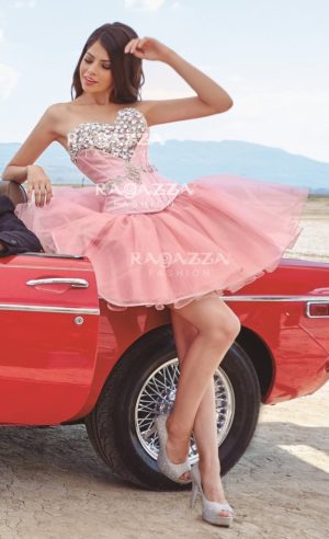 A beautiful woman in a pink Quinceanera dress sitting on a red car