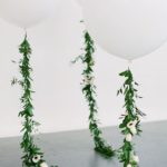 Quinceanera decorations with a bunch of white balloons and green garlands