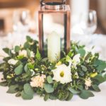 Quinceanera table with an open lantern floral centerpiece, featuring a candle and flowers