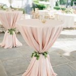 A Quinceanera themed cocktail table with a pink tablecloth and floral decorations
