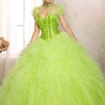 A woman in a green dress posing for a picture wearing a gown Quinceañera dresses