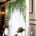 Quinceanera celebration with a hessian backdrop and a room adorned with a bunch of flowers on the wall