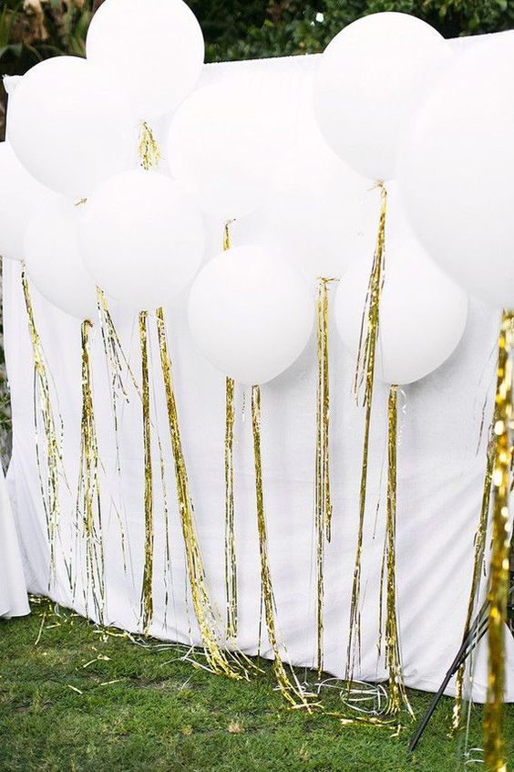White streamer backdrop balloon, a bunch of white balloons sitting on top of a lush green field for a Quinceanera celebration
