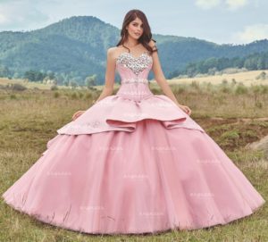 A woman in a pink Quinceañera dress standing in a field of gown Quinceañera dresses.