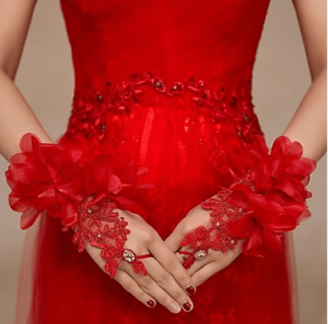 Quinceanera image: a woman in a red dress with red flowers on her hands wearing Pakistani bridal gloves.