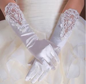 A close up of a person wearing white Quinceanera gloves