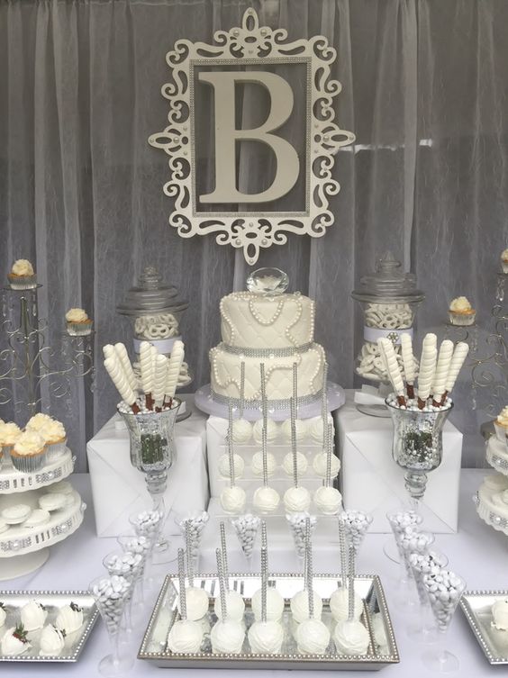 Quinceanera candy table with lots of desserts and cupcakes