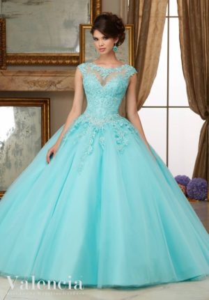 Aqua Quinceañera dress creation: a woman in a blue ball gown standing in front of a mirror