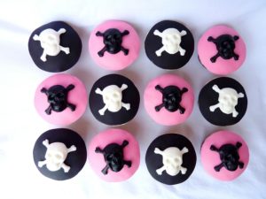 A group of cupcakes with pink and black frosting arranged in a punk rock style for a Quinceanera celebration.