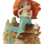 A beautiful Precious Moments figurine of a little mermaid sitting on a rock, perfect for a Quinceanera celebration
