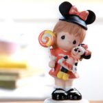 A Quinceanera themed image featuring a stuffed toy Minnie Mouse and a figurine of a little girl holding a teddy bear.
