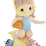 A Quinceanera themed image featuring a stuffed toy Figurine and a figurine of a little girl in a diving suit.
