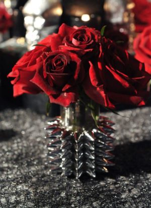 A beautiful floral design featuring a bunch of red garden roses in a vase on a table for a Quinceanera celebration