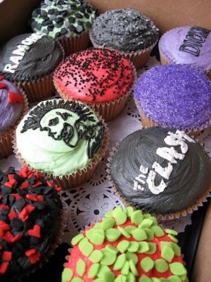 A box full of punk rock cupcakes decorated with different designs for a Quinceanera celebration.