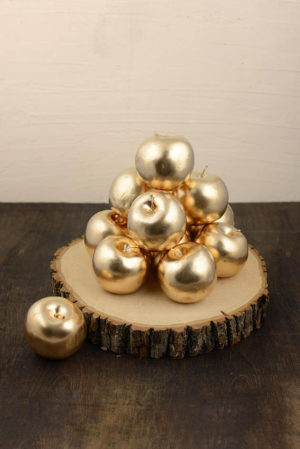A pile of gold ornaments sitting on top of a piece of wood, surrounded by pearl apples