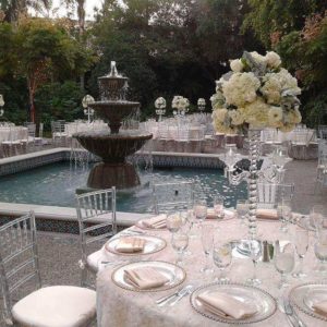 A beautifully decorated Quinceanera table set for a formal event with a water feature in the background